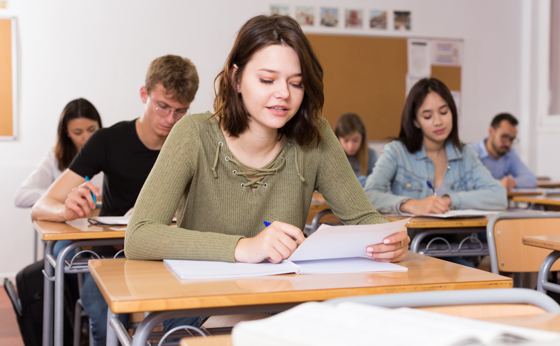 Smiling schoolgirl is learning and answering the question on paper