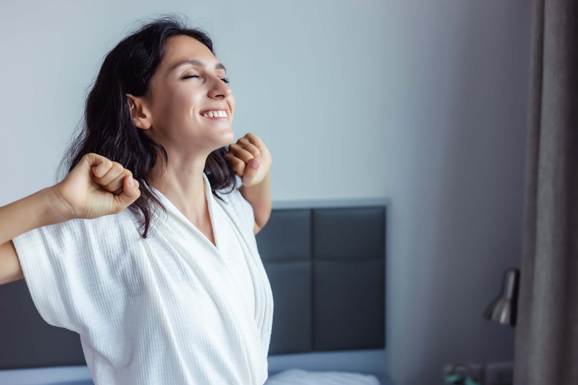 Beautiful woman waking up on her bed at bedroom Young Female stretching and smiling overjoyed Beauty Lady wake up meet good weekend early morning Young lady feel optimistic at home with smile face