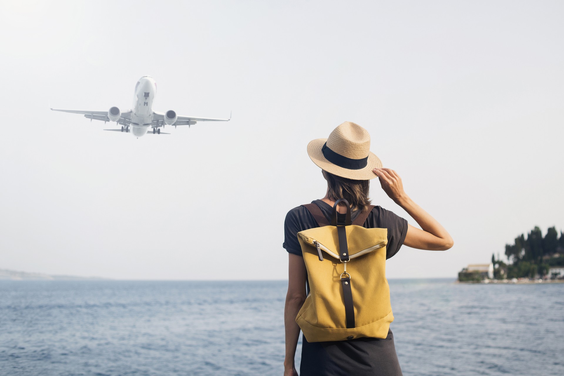 Woman tourist looking at flying plane. Travel concept